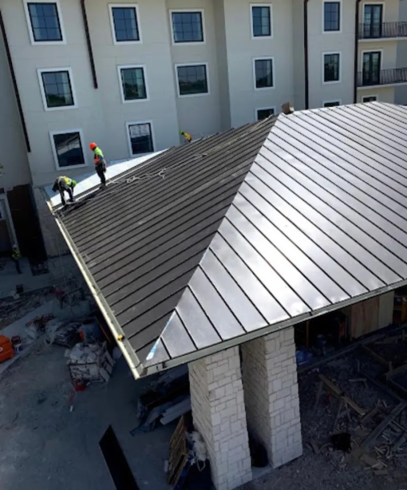 Crew installing standing seam metal roof panels on a commercial project in Vienna